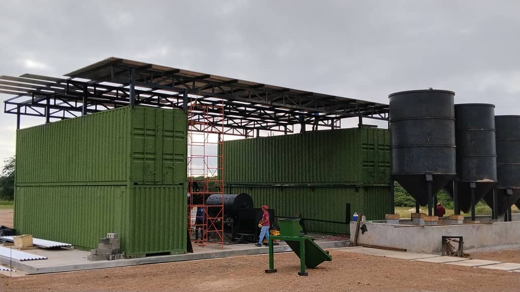 Estructura modular con contenedores, techo metálico y silos en planta